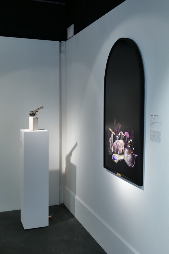 Installation view with a sculpture on a plinth beside a framed work