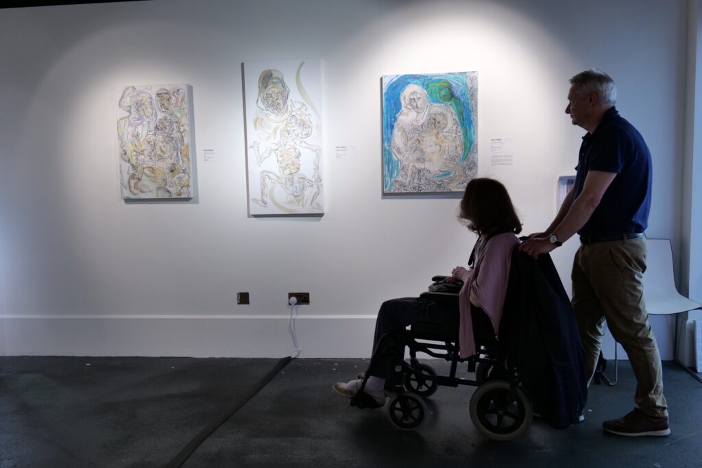 Visitors viewing three framed works on the gallery wall