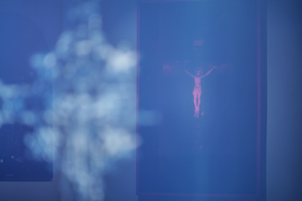 Blue and magenta work showing a crucified figure beside a luminous cross