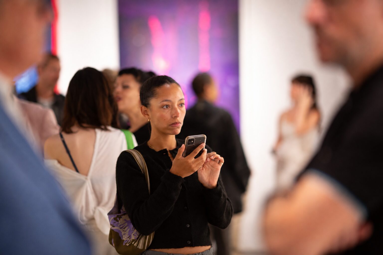 Visitors at a Chase Culture private view, one photographing a work on the gallery wall